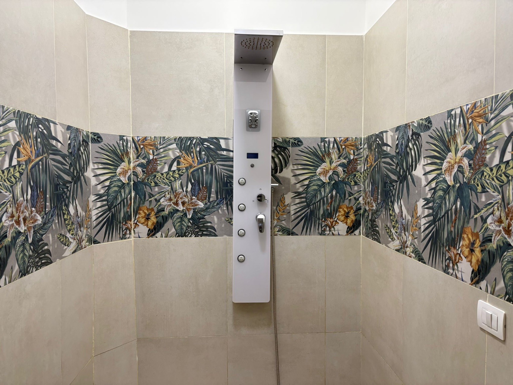 La doccia emozionale di Oasi del Benessere: colonna idromassaggio con getti e fascia di piastrelle a motivi tropicali